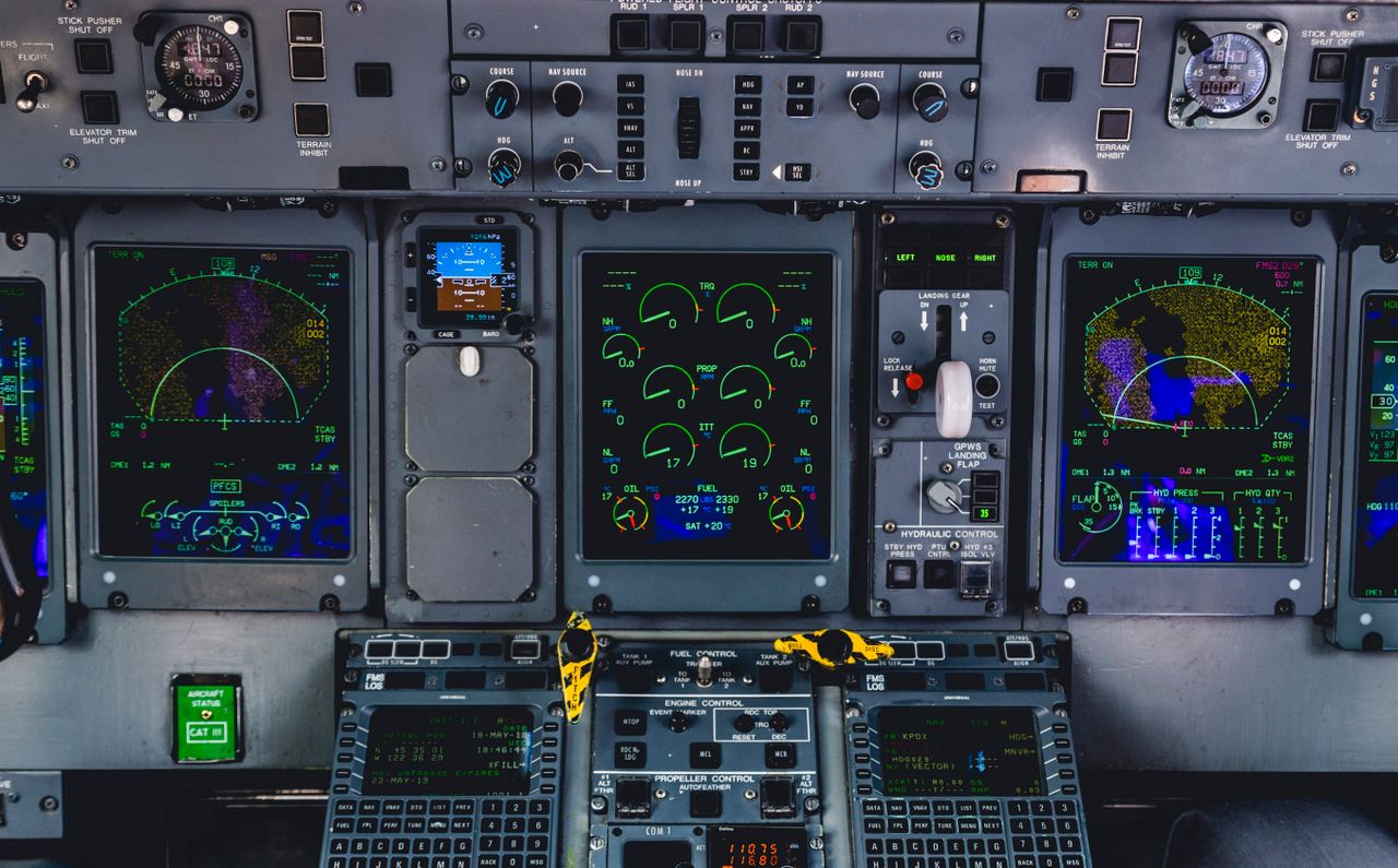 Detailed view of an aircraft cockpit control panel with various screens and controls.