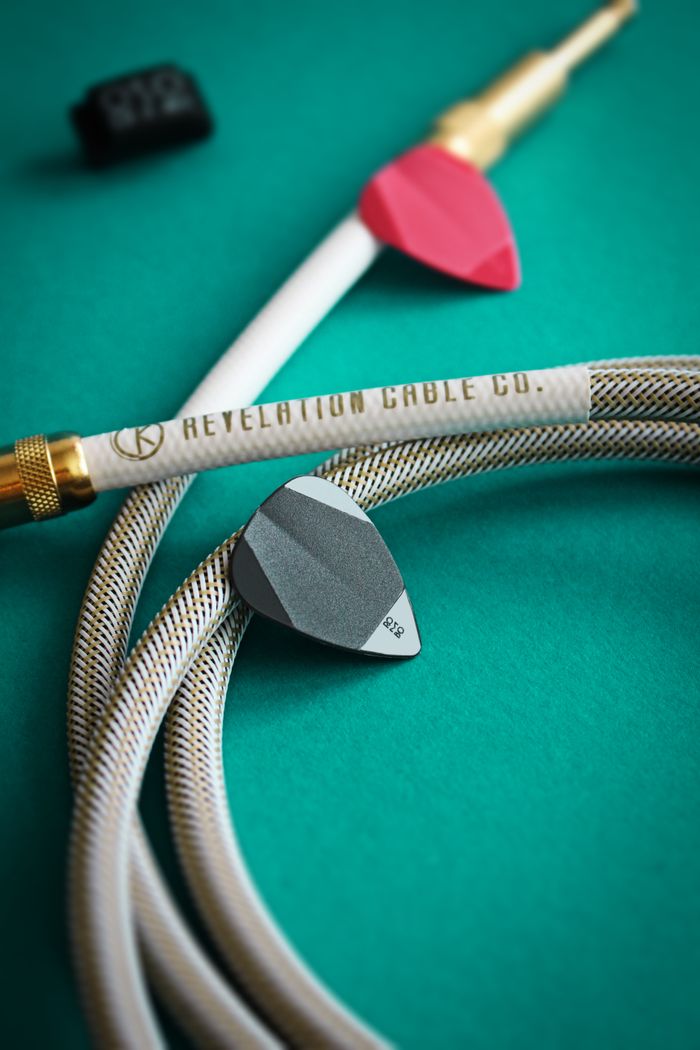 Detailed photo of guitar picks and cables on a textured green surface for music enthusiasts.